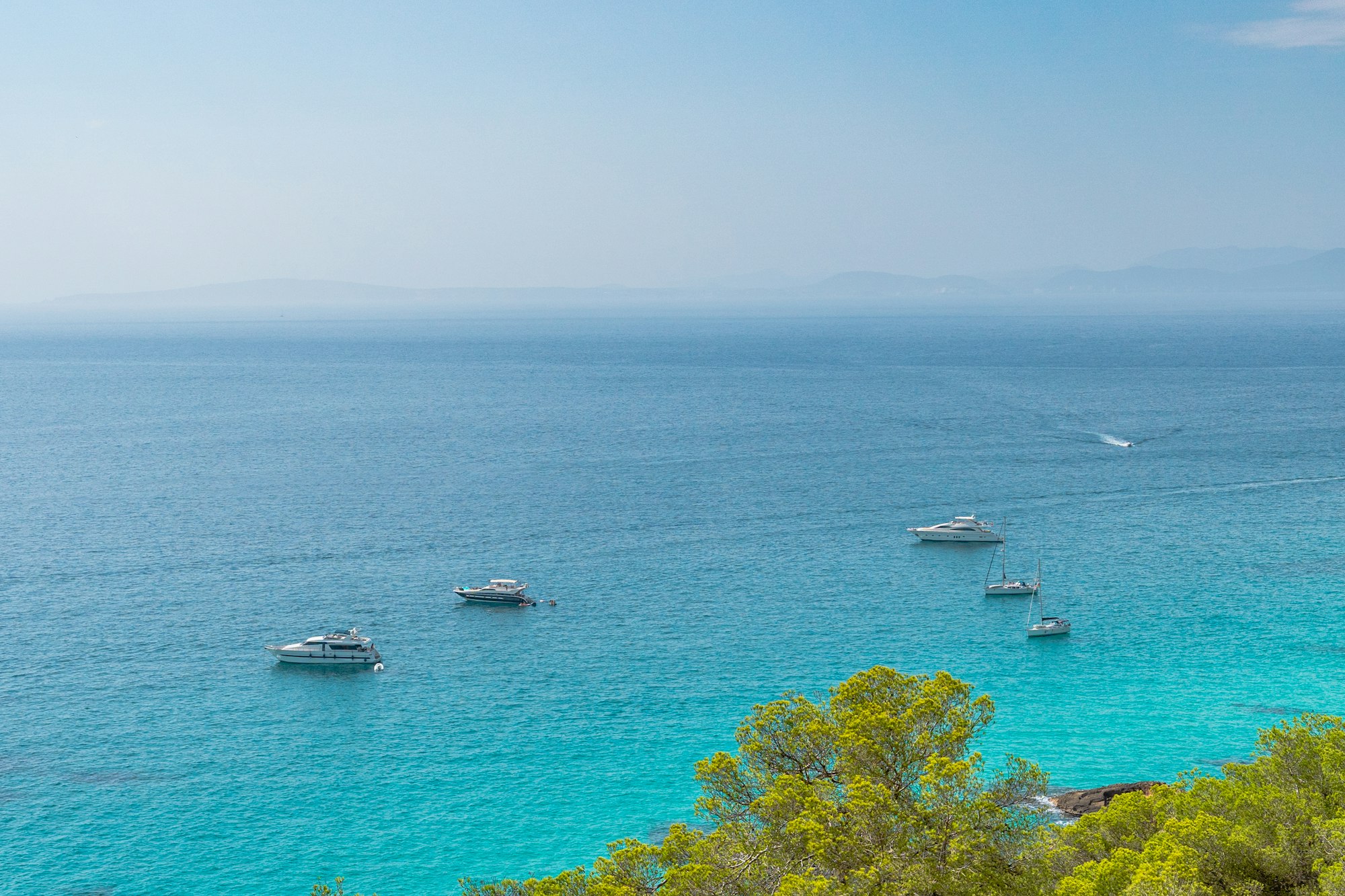 Boote in Küstennähe mit kristallklarem Wasser in Les Palmeres auf der Insel Mallorca